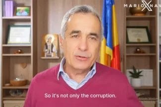 Calin-Georgescu_36d9891e6c - Știri de azi Știri de azi | Călin Georgescu, interviu EVENIMENT pentru Mario Nawfal, după ce i s-a deschis doar penal în România - Știri de azi | Călin Gergescu stă în fața unei cămări cu cărți, vorbind în timpul unui interviu video. În fundal se observă un steag al României și diverse obiecte decorative.