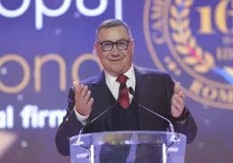 "Fostul premier Victor Ponta vorbind la un eveniment public, exprimându-se cu gesturi animate în timpul unui discurs, în timp ce poartă un costum elegant.