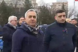 1_7b3df64c99 - Știri de azi Știri de azi | Călin Georgescu, mesaj pentru forțele de ordine prezente la protest: Apărați mai bine poporul român de sistemul corupt, NU sistemul corupt de poporul român - Știri de azi | Călin Georgescu însoțit de George Simion la un eveniment public, purtând un fular și o geacă albastră, cu o expresie serioasă, discutând cu forțele de ordine la un miting.