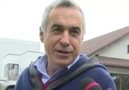 Călin Georgescu vorbind cu presa în fața unei clădiri, exprimându-și nemulțumirea cu privire la măsurile impuse de autorități, într-un cadru informal.