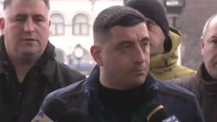 Știri de azi | Apelul liderului suveraniștilor, George Simion, din mijlocul manifestanților. „Le cer românilor să fie pașnici, să colaboreze cu autoritățile” - Știri de azi | George Simion înconjurat de manifestanți, adresându-se presei într-un mediu urban, cu o expresie serioasă și determinată