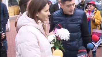 Anca Alexandrescu, alături de George Simion, discută cu jurnaliștii și locuitorii Capitalei în timpul unei acțiuni de campanie, ținând în mână flori oferite de susținători.