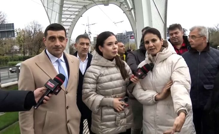 Anca Alexandrescu și George Simion la stația de tramvai Eroii Revoluției, criticând investiția de 5,3 milioane de euro într-o structură decorativă, în timp ce bucureștenii așteaptă tramvaiul în frig și ploaie.